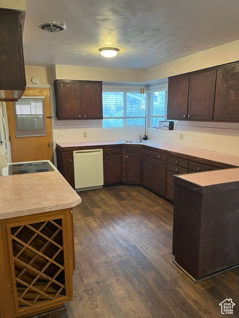 Kitchen featuring dishwasher, dark hardwood / wood-style floors, backsplash, and dark brown cabinets