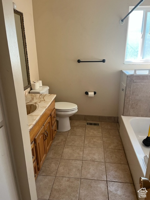 Bathroom with vanity, toilet, tile patterned floors, and a washtub