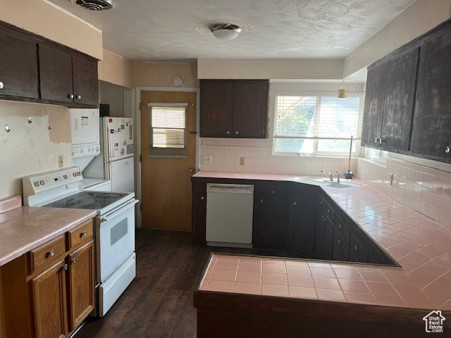 Kitchen with a textured ceiling, white appliances, tile countertops, tasteful backsplash, and dark hardwood / wood-style flooring