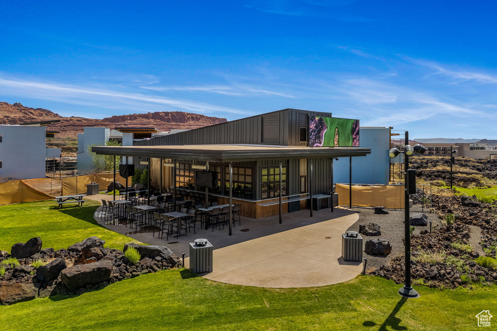 Back of house with a patio area, a mountain view, and a lawn