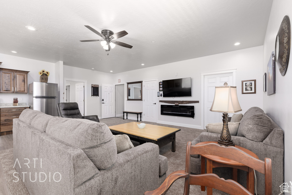 Living room featuring ceiling fan, carpet, and a fireplace