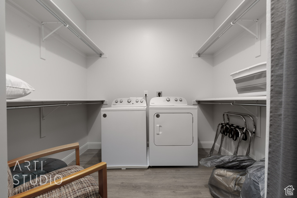 Washroom with washing machine and clothes dryer and light hardwood / wood-style flooring