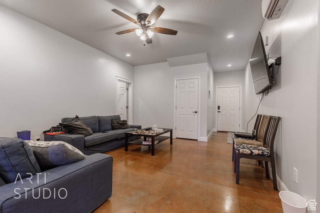 Living room featuring ceiling fan, concrete floors, and a wall mounted air conditioner