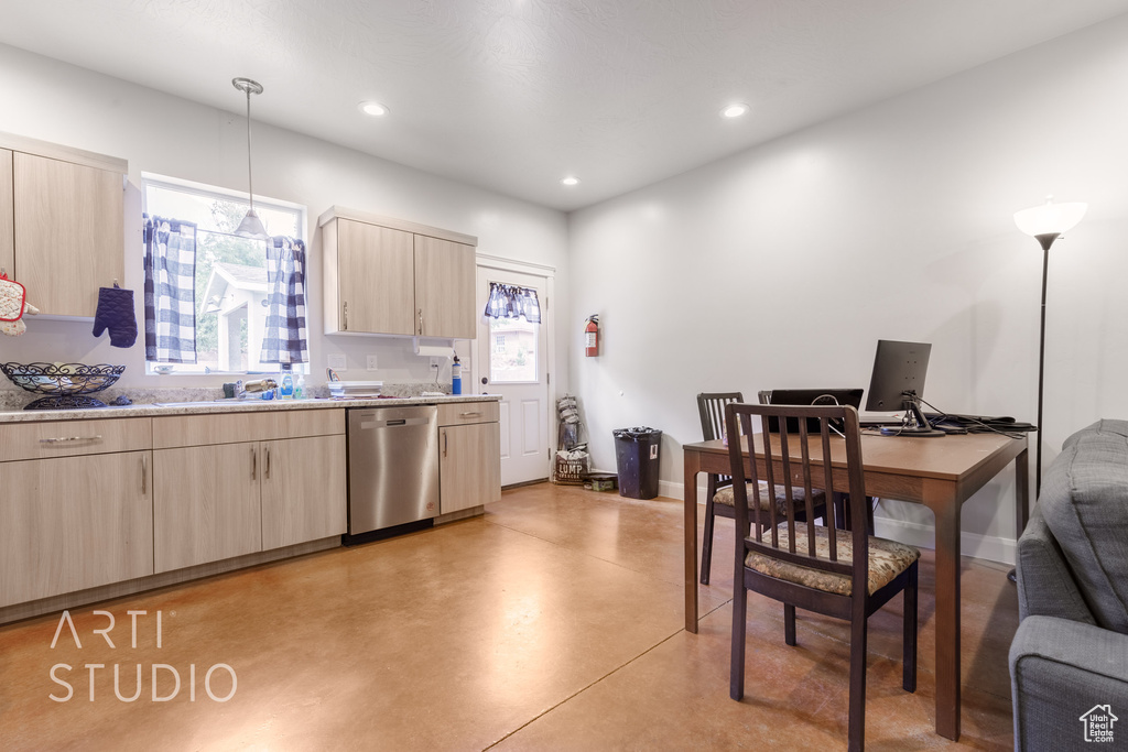 Kitchen with light brown cabinets, stainless steel dishwasher, light stone countertops, sink, and decorative light fixtures