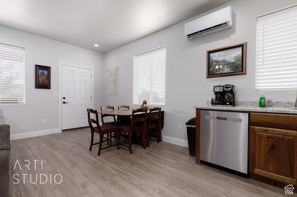 Dining room featuring light wood-type flooring and a wall mounted air conditioner