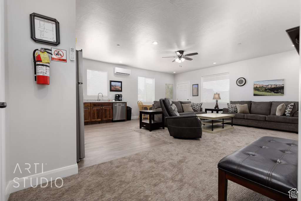 Living room featuring ceiling fan, sink, light hardwood / wood-style floors, and a wall mounted AC