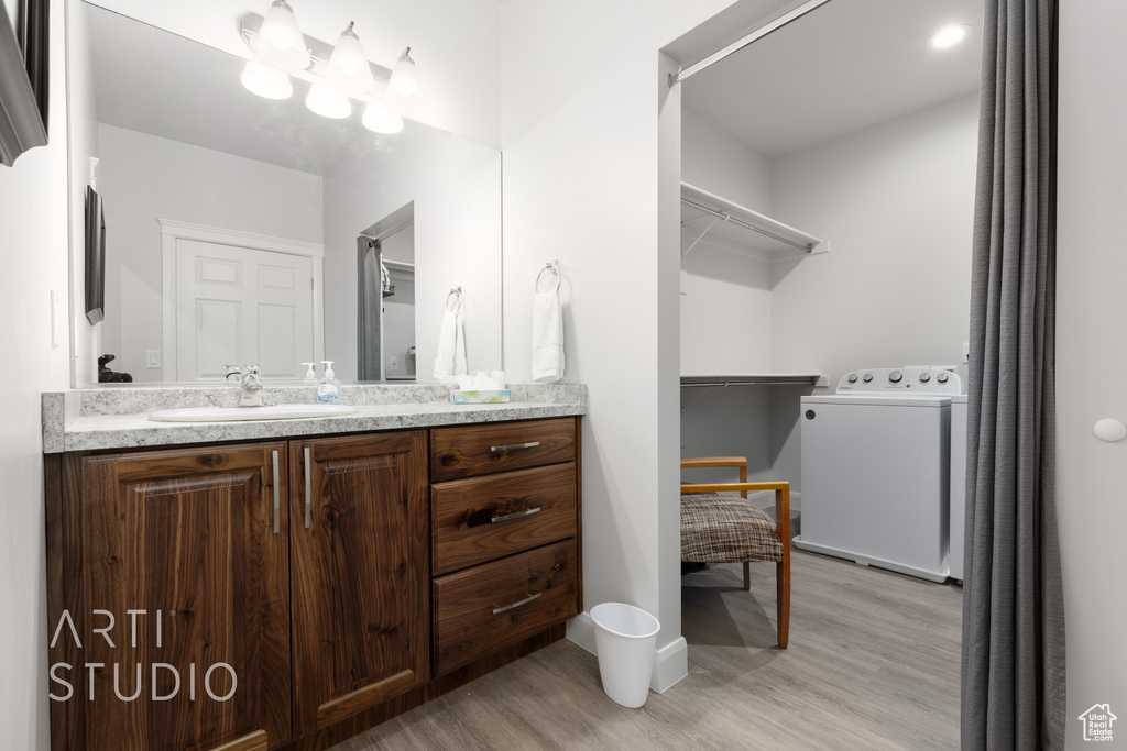 Bathroom featuring hardwood / wood-style flooring, vanity, and washer / dryer