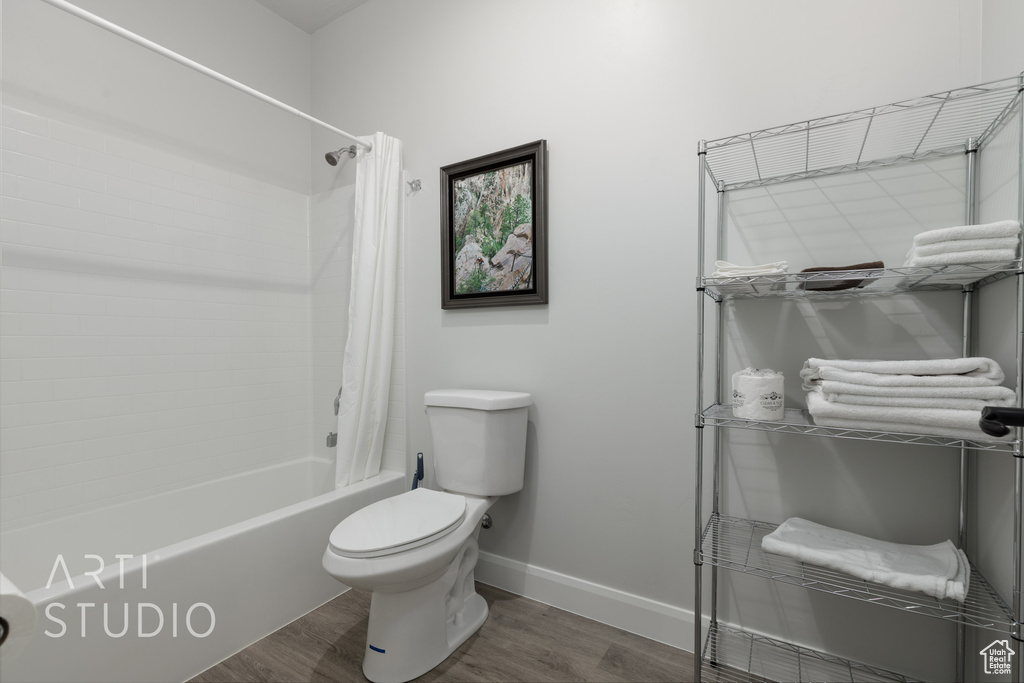 Bathroom featuring toilet, wood-type flooring, and shower / bath combo