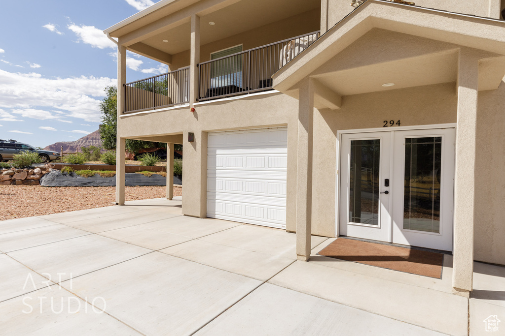 Property entrance with a balcony, french doors, and a garage