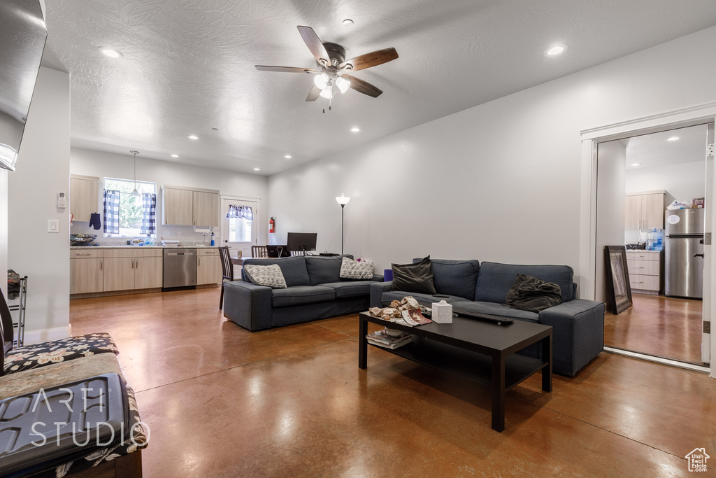 Living room featuring ceiling fan and concrete flooring