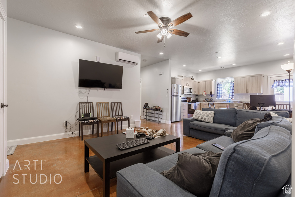 Living room with ceiling fan, light hardwood / wood-style floors, and an AC wall unit