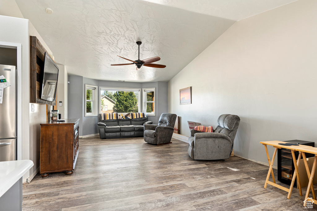 Living room featuring lofted ceiling, ceiling fan, hardwood / wood-style flooring, and a textured ceiling