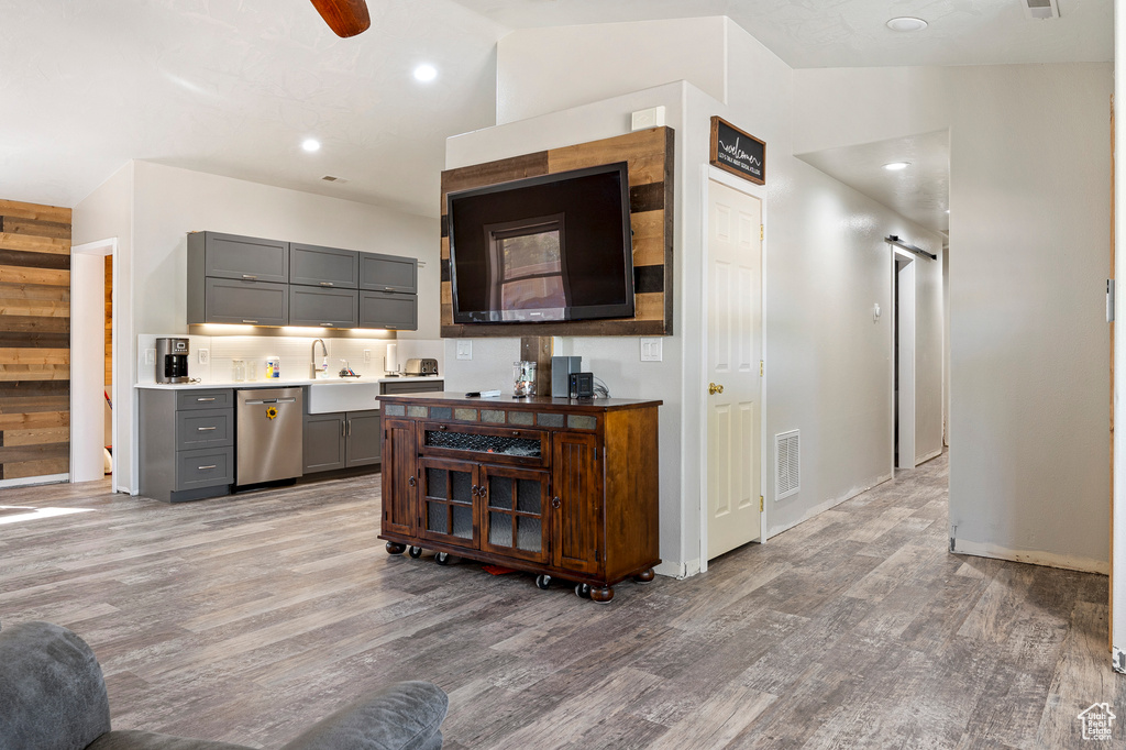 Kitchen featuring gray cabinets, light wood-type flooring, lofted ceiling, and stainless steel dishwasher