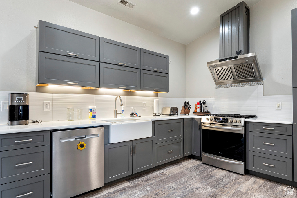 Kitchen with appliances with stainless steel finishes, gray cabinetry, and light hardwood / wood-style flooring