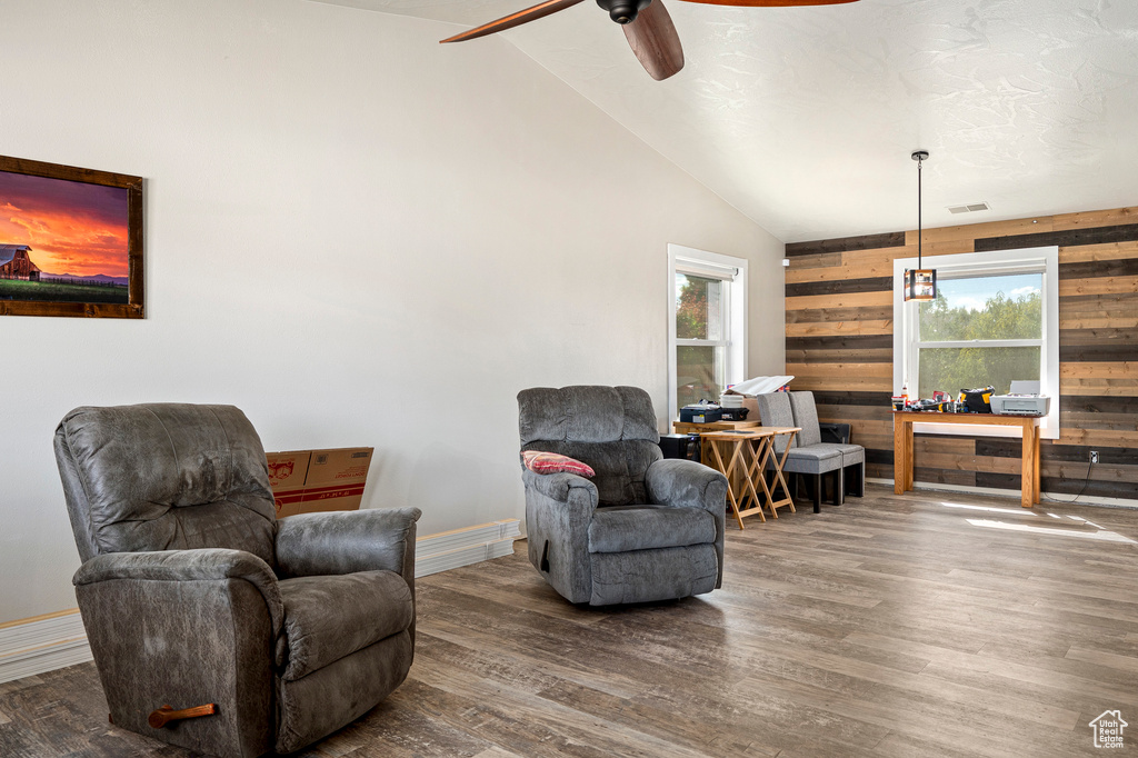 Living area with dark wood-type flooring, wood walls, and a wealth of natural light