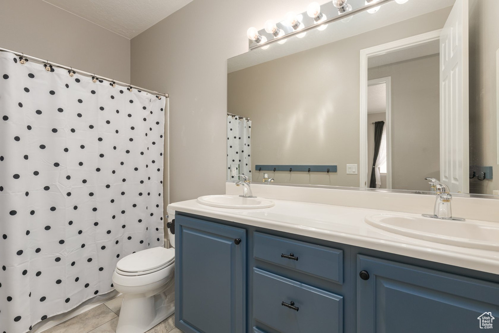 Bathroom featuring tile patterned floors, toilet, curtained shower, and vanity