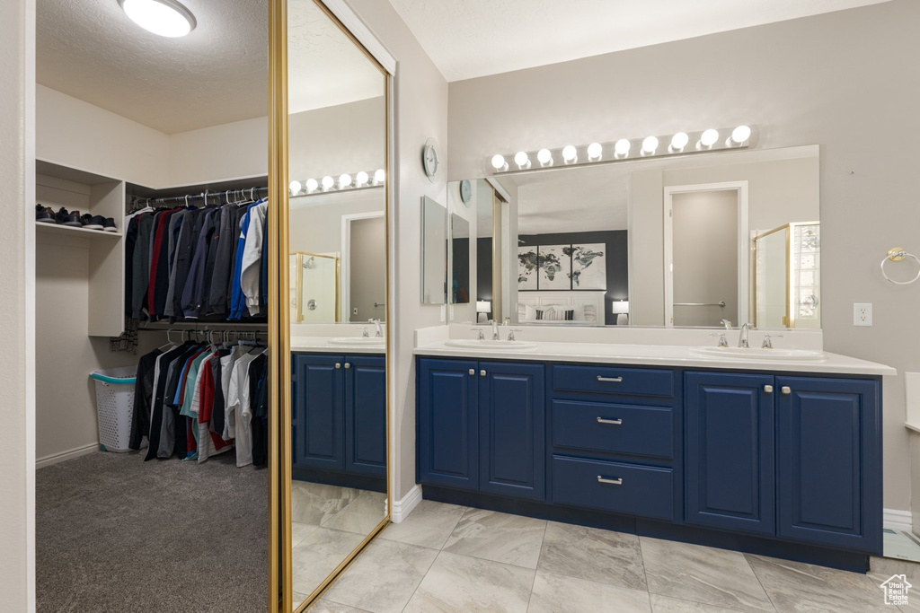 Bathroom featuring a textured ceiling, vanity, and a shower with door