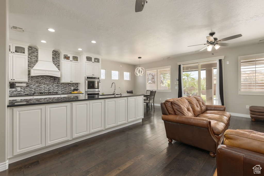 Kitchen with plenty of natural light, premium range hood, ceiling fan, and hanging light fixtures