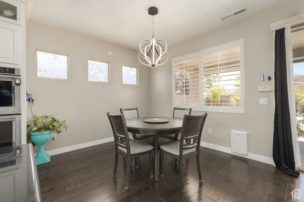 Dining room featuring a healthy amount of sunlight, a notable chandelier, and dark wood-type flooring