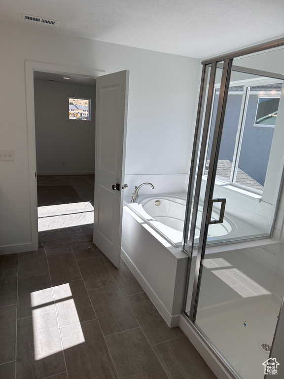 Bathroom featuring shower with separate bathtub, tile patterned floors, and a healthy amount of sunlight