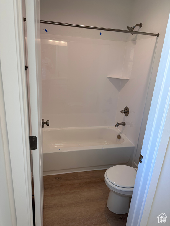 Bathroom with shower / tub combination, hardwood / wood-style flooring, and toilet