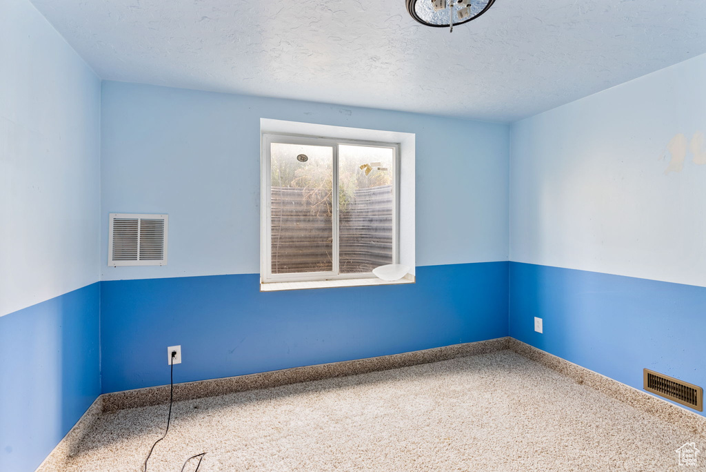 Empty room featuring a textured ceiling and carpet flooring