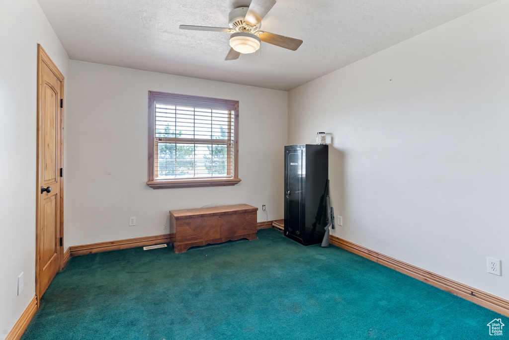 Unfurnished bedroom with ceiling fan and dark colored carpet