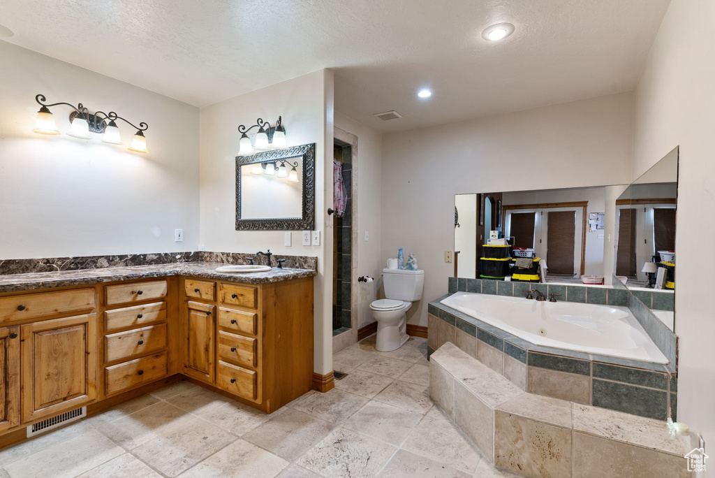 Full bathroom featuring a textured ceiling, vanity, toilet, and shower with separate bathtub