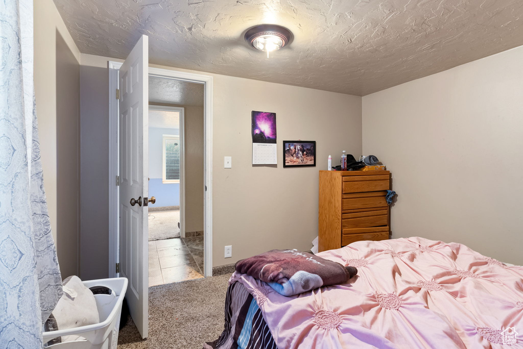 Bedroom with light colored carpet and a textured ceiling