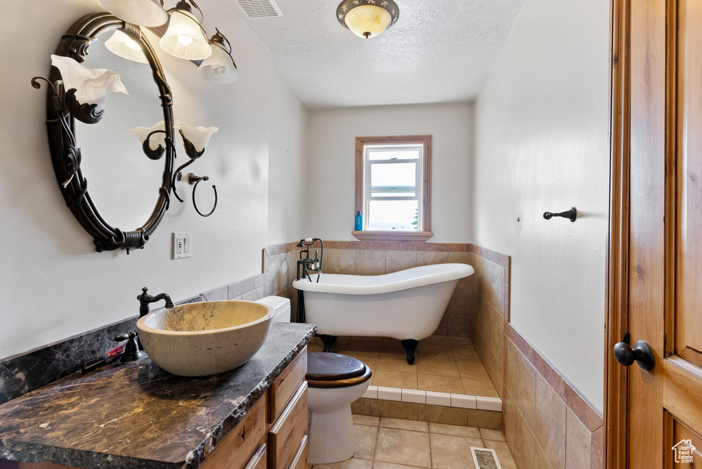 Bathroom with vanity, a bathing tub, tile patterned flooring, tile walls, and toilet