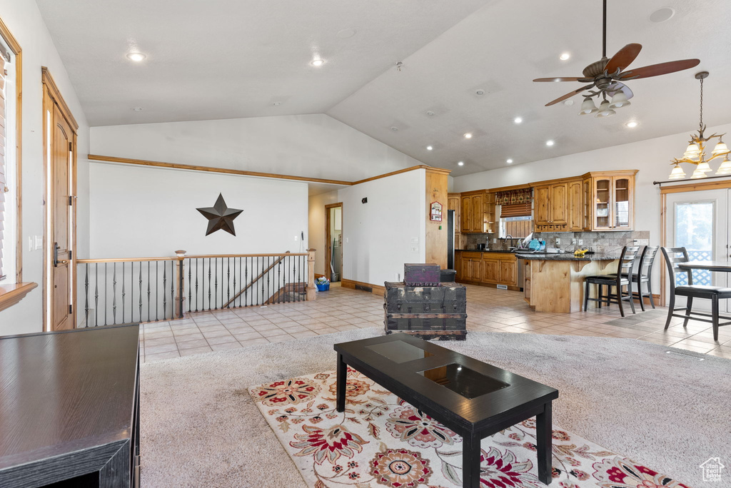 Carpeted living room featuring high vaulted ceiling and ceiling fan with notable chandelier