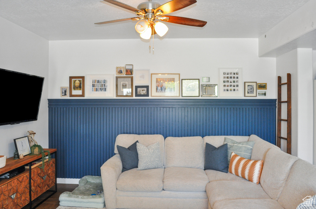 Living room with ceiling fan, wood-type flooring, and a textured ceiling