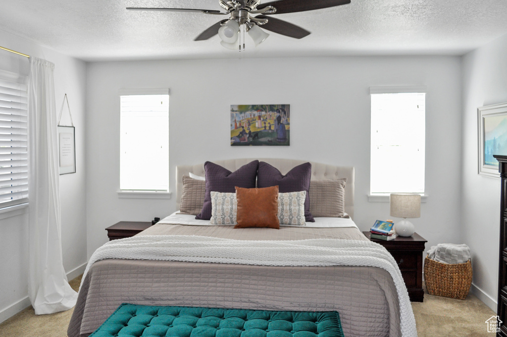 Carpeted bedroom featuring a textured ceiling and ceiling fan