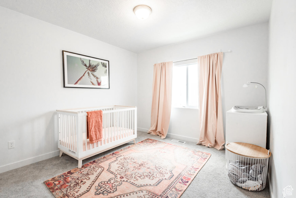 Bedroom with light carpet and a crib