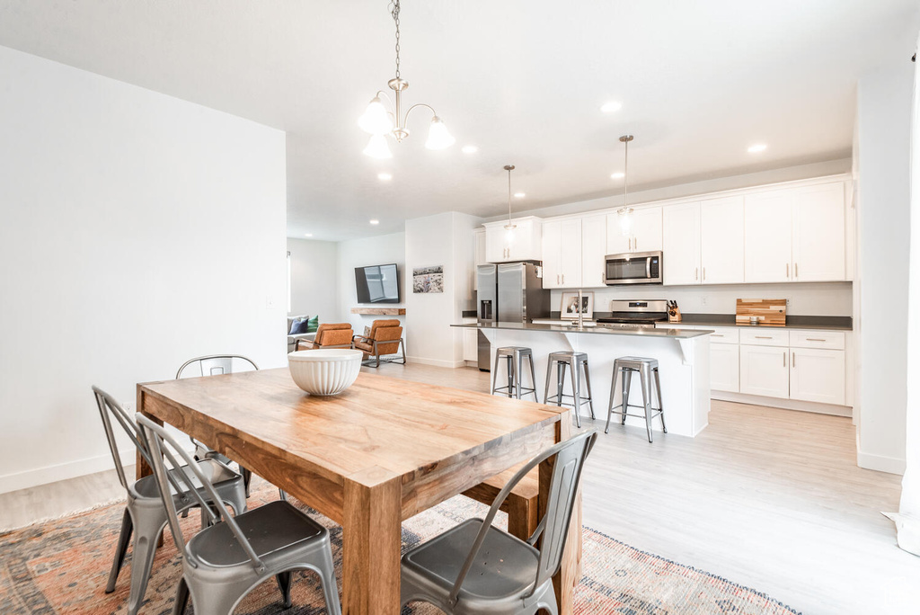 Dining space with sink, a notable chandelier, and light hardwood / wood-style flooring