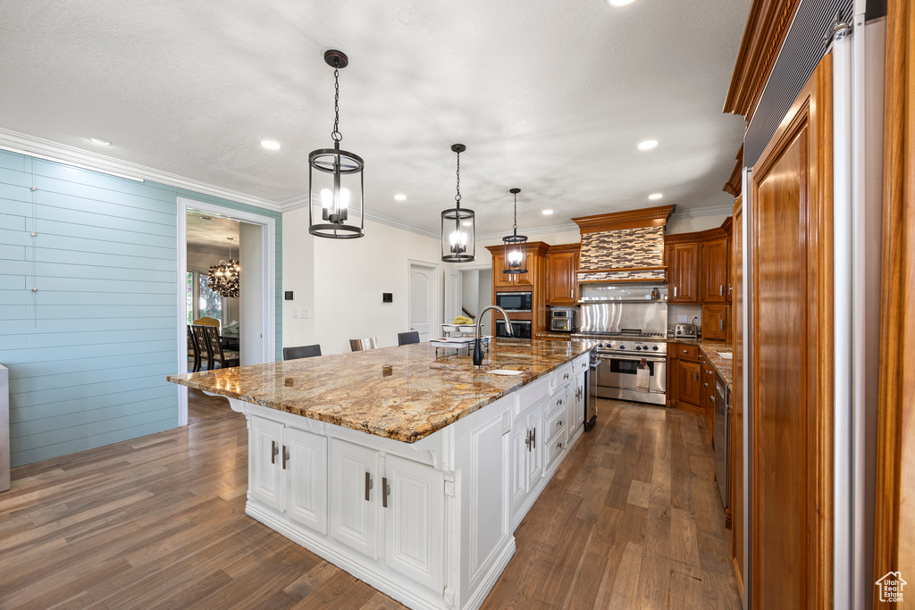 Kitchen with dark hardwood / wood-style floors, decorative light fixtures, custom range hood, white cabinetry, and a large island