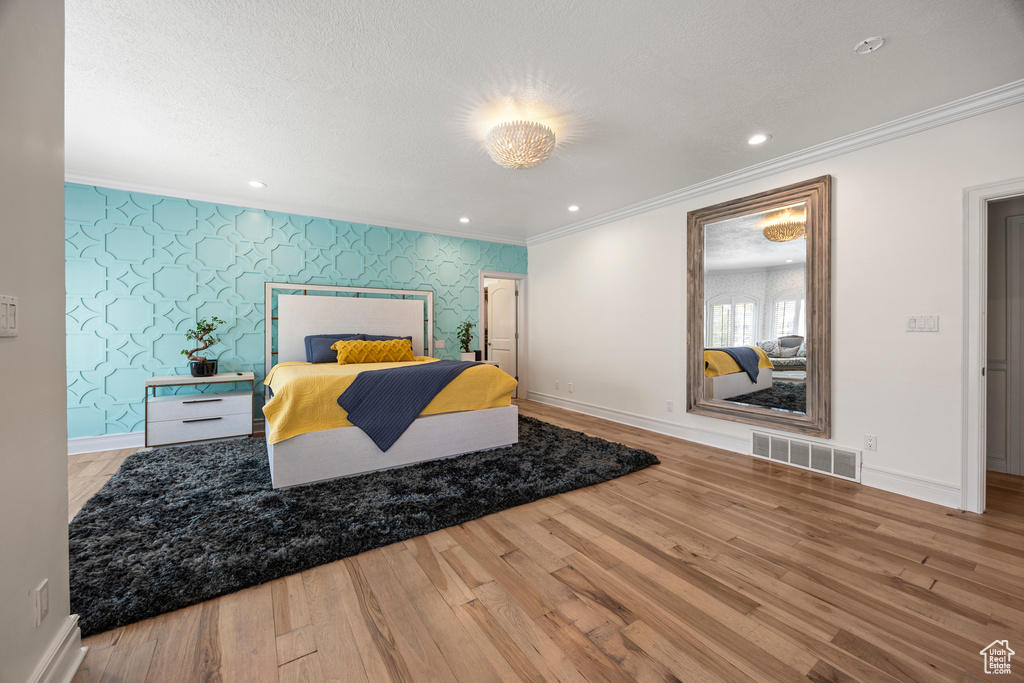 Bedroom with hardwood / wood-style floors, ornamental molding, and a textured ceiling