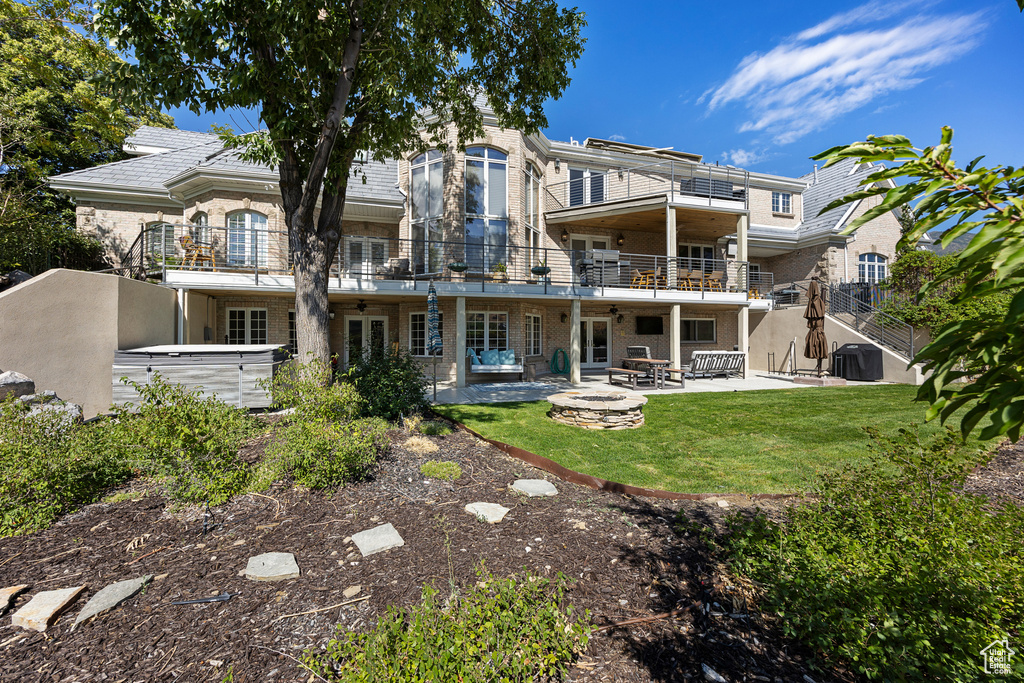 Rear view of house with a balcony, an outdoor fire pit, a yard, and a patio area