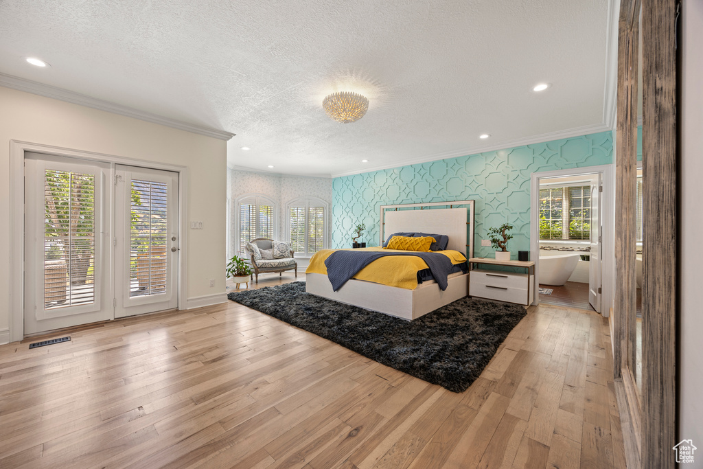 Bedroom featuring light wood-type flooring, crown molding, a textured ceiling, and access to outside