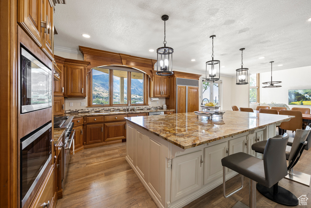 Kitchen with a wealth of natural light, a spacious island, a breakfast bar area, and built in appliances