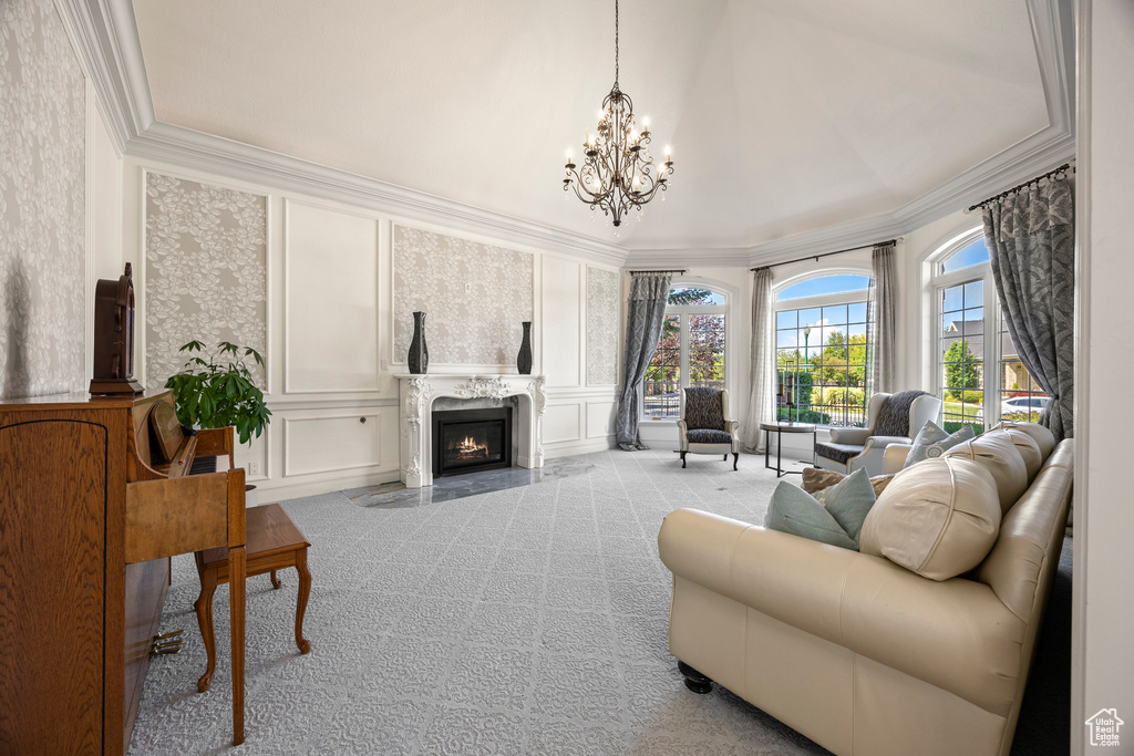 Living room featuring ornamental molding, a high end fireplace, light carpet, and an inviting chandelier