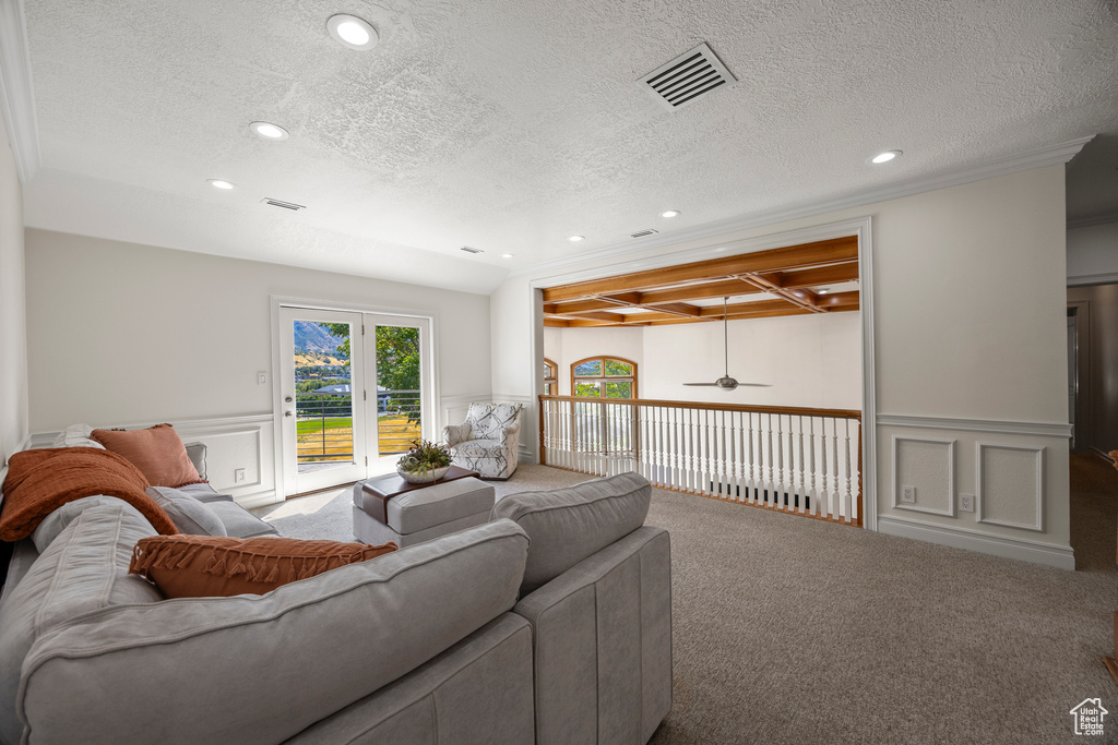 Carpeted living room with a textured ceiling, ceiling fan, and ornamental molding