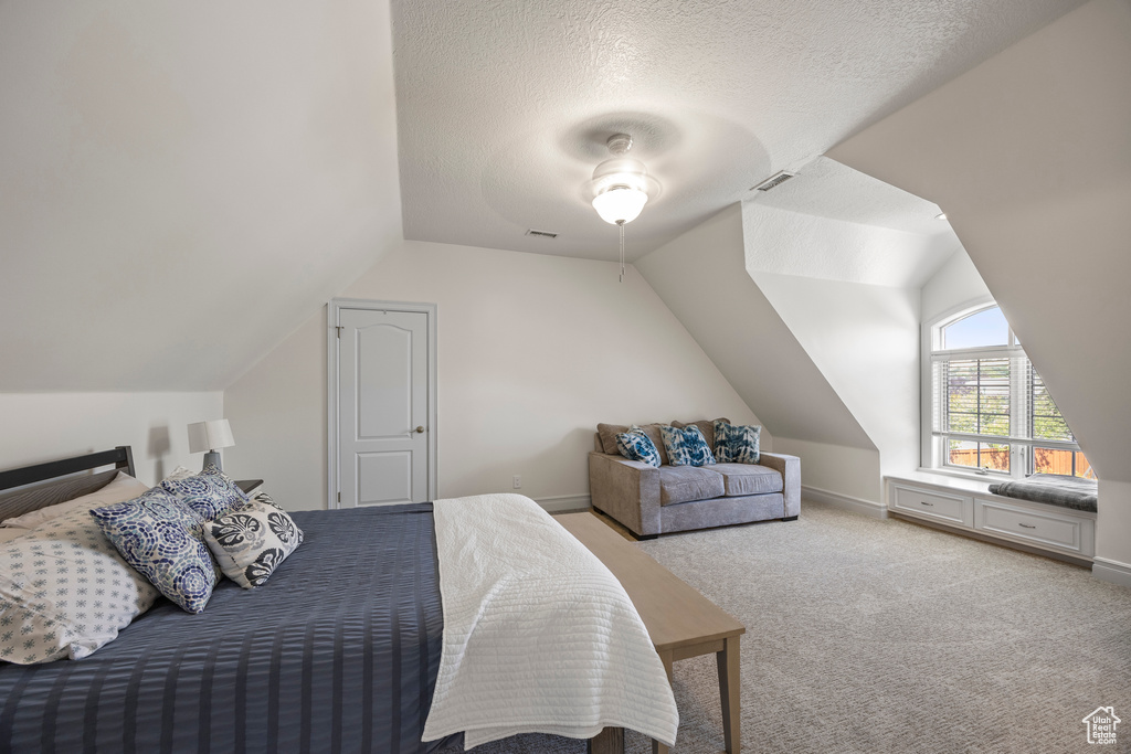 Bedroom with ceiling fan, a textured ceiling, light carpet, and vaulted ceiling