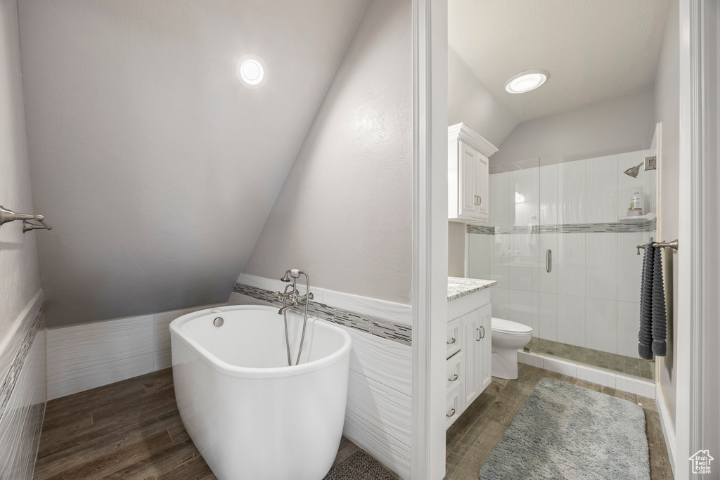 Full bathroom with vanity, vaulted ceiling, separate shower and tub, wood-type flooring, and toilet