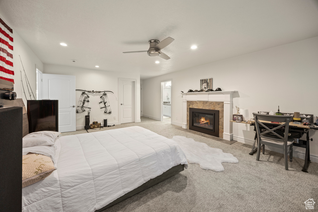 Bedroom with ceiling fan, light colored carpet, and a tile fireplace