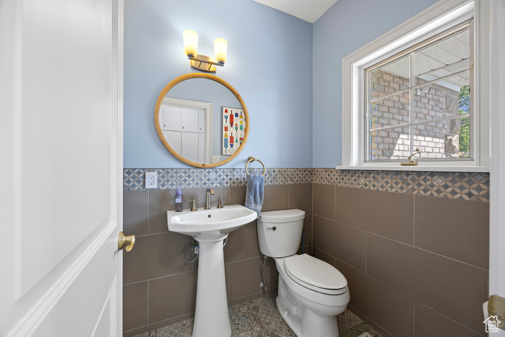 Bathroom with tile walls, toilet, and tile patterned floors