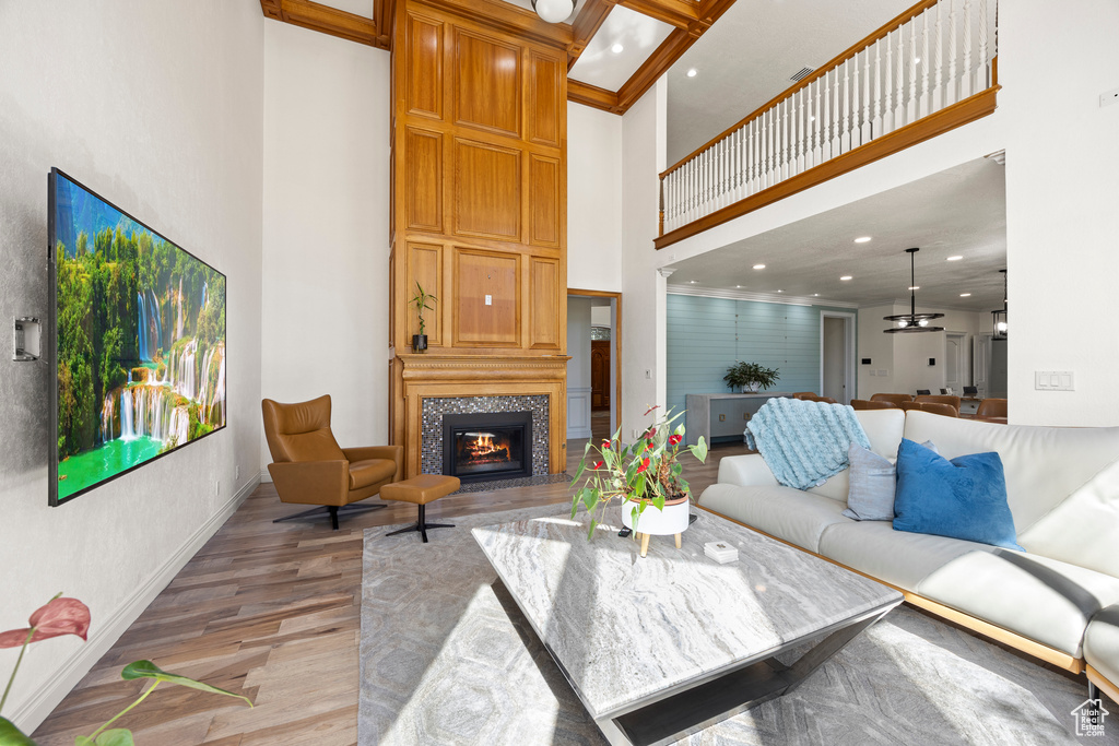 Living room with a towering ceiling, ornamental molding, and light hardwood / wood-style flooring