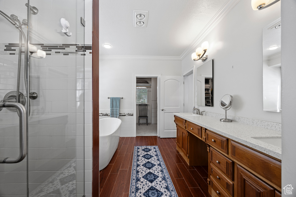 Bathroom featuring crown molding, vanity, and plus walk in shower