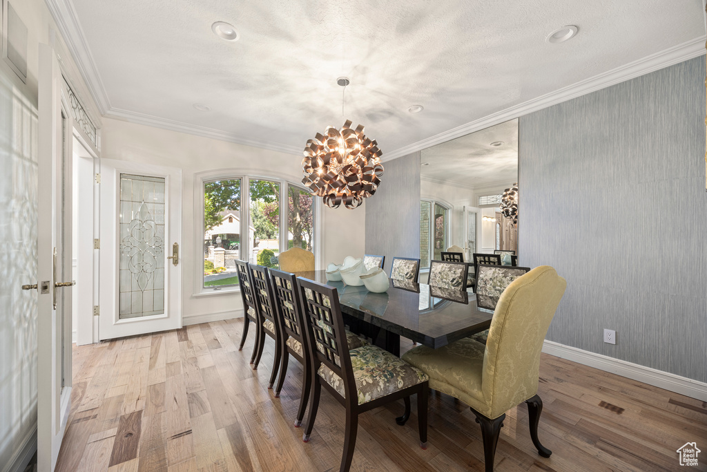 Dining space with ornamental molding, a chandelier, and light hardwood / wood-style floors