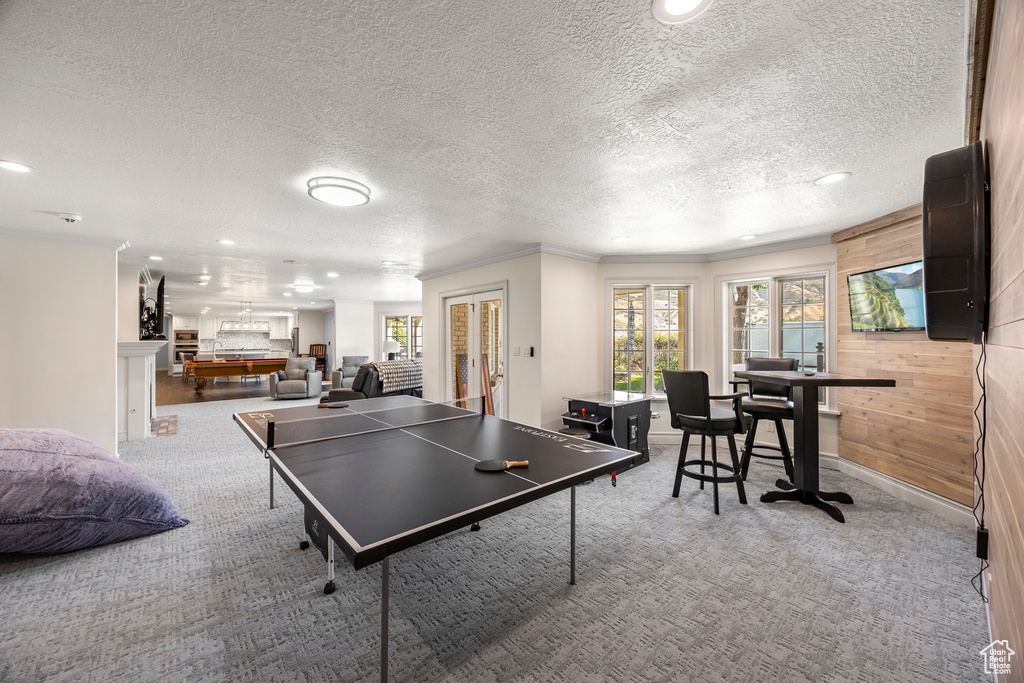 Rec room featuring pool table, wooden walls, crown molding, french doors, and a textured ceiling